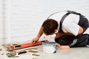 Contractor checking newly laid floor tiles with a level during a Hayward home remodel